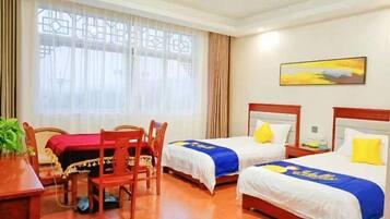 A hotel room with two beds, a desk, and a chair.