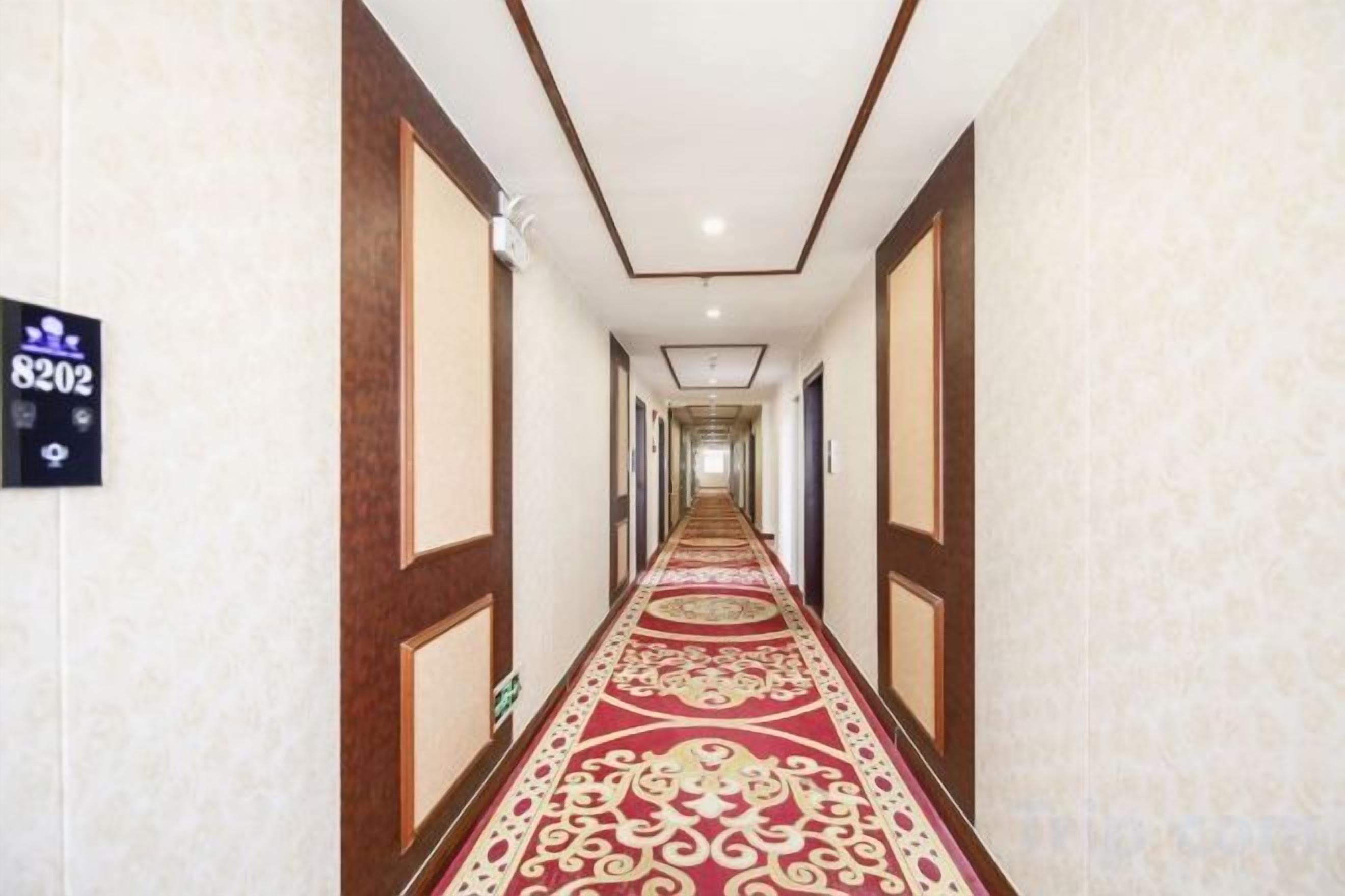 A long, narrow hotel corridor with a patterned carpet and wooden paneling on the walls.