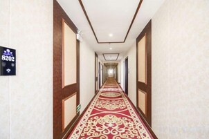 Un largo y estrecho pasillo de hotel con alfombra estampada y paneles de madera en las paredes.