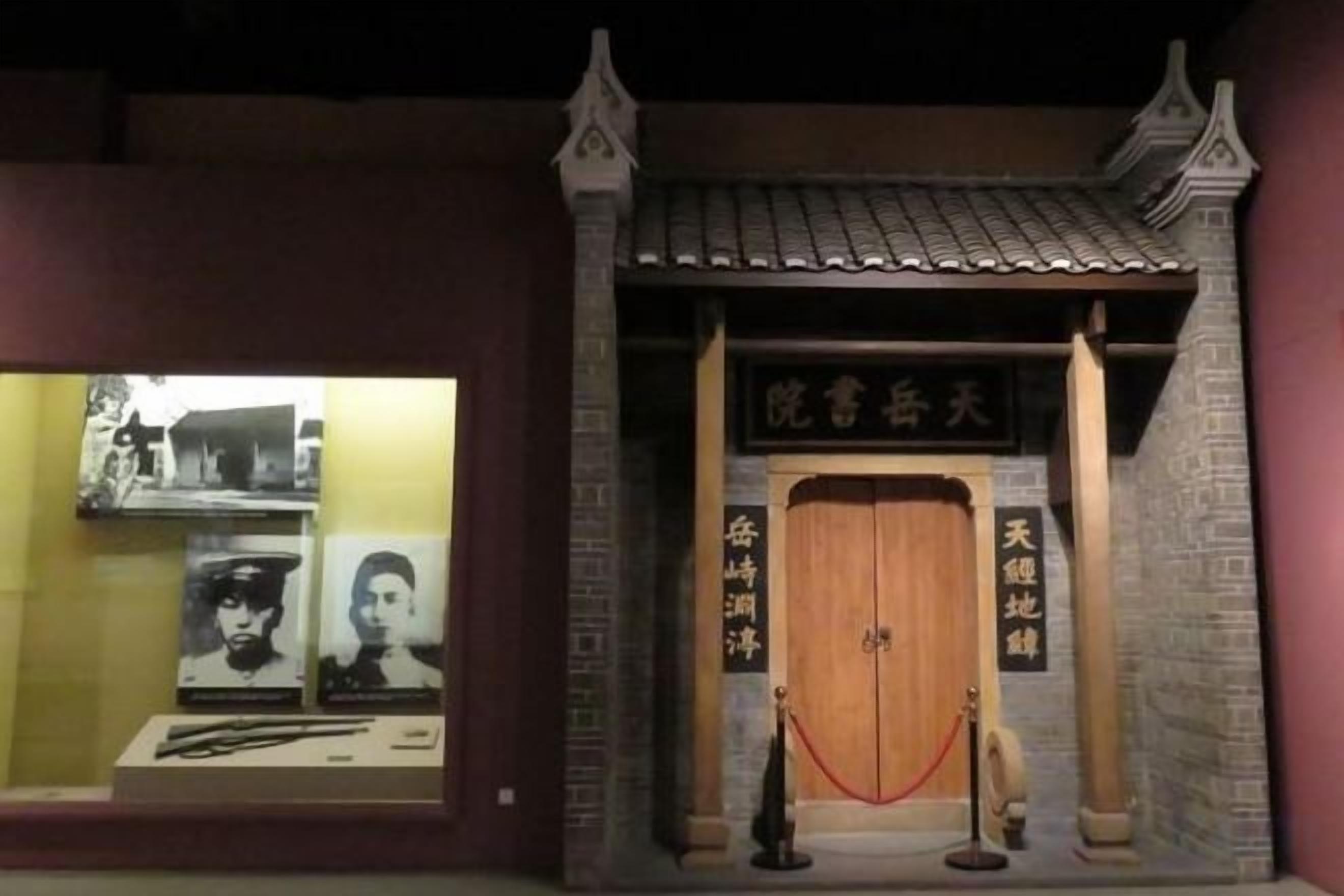 Une façade de bâtiment traditionnel chinois, avec une porte en bois, une barrière faite d’une corde rouge et une enseigne avec des caractères chinois.