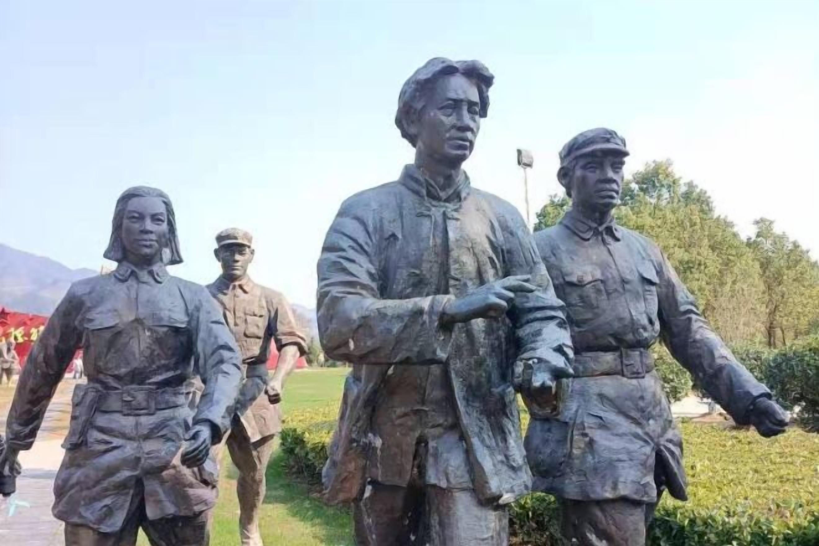 Une statue représentant trois personnages en uniforme, vraisemblablement des militaires, dans un parc.