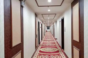 A hotel corridor with a patterned carpet, wooden doors, and a ceiling with recessed lighting. - Starlight Hotel(Jinggangshan Railway Station Store) (Jinggangshan City)