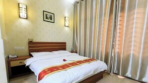 Una camera d'albergo con un letto, un comodino, una lampada e tende.