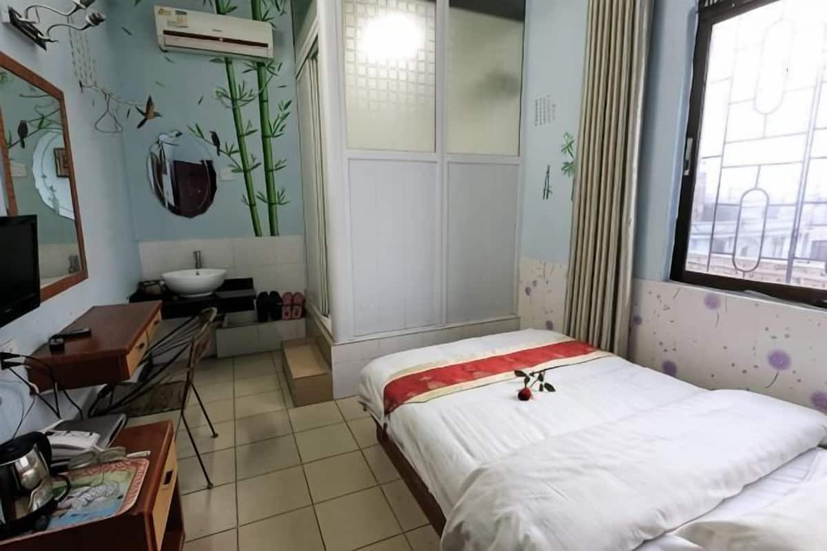 Ein Schlafzimmer mit einem Bett, einem Schreibtisch, einem Stuhl, einem Spiegel, einem Waschbecken und einem Fenster mit Blick.