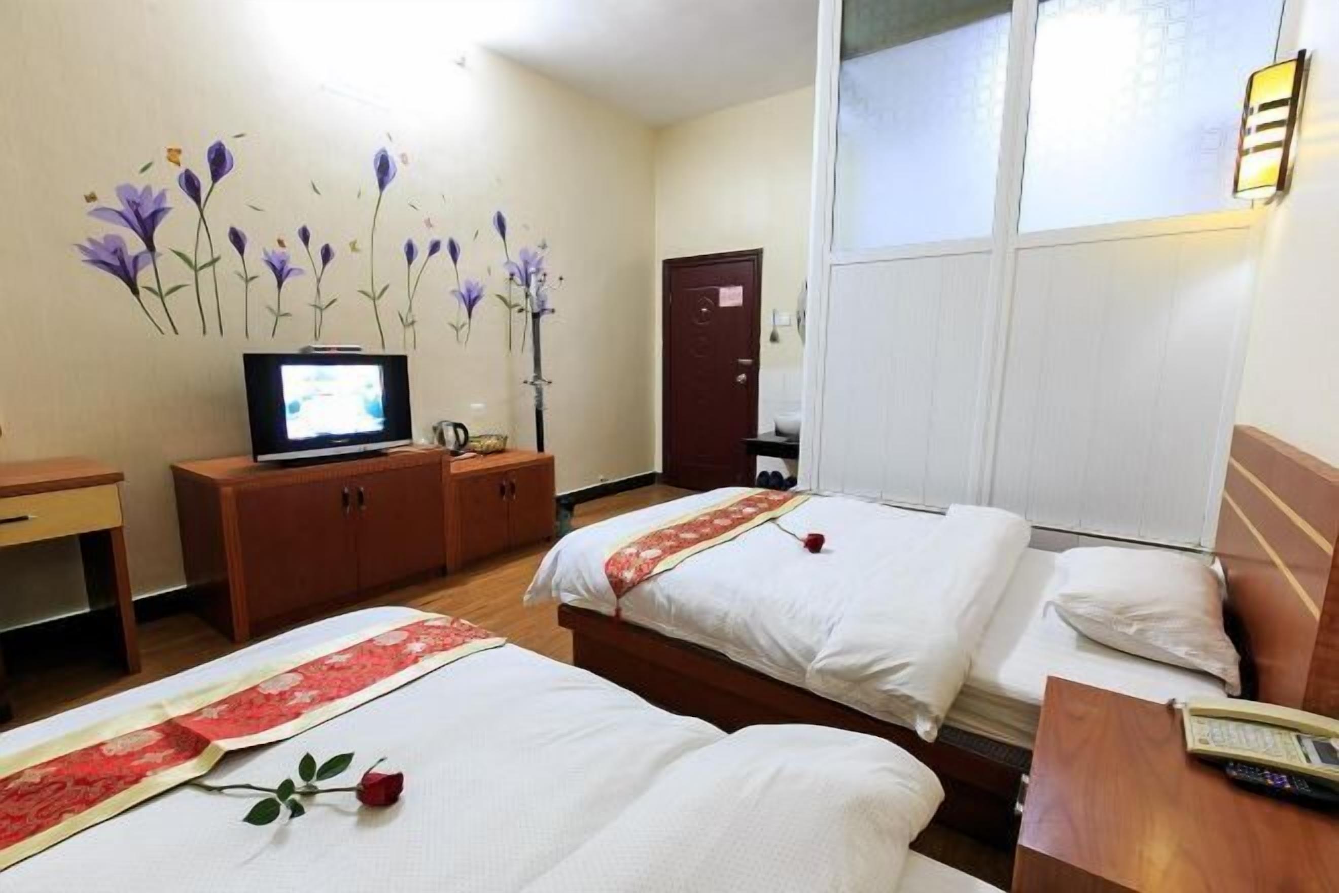 A hotel room with two beds, a TV, a desk, and a wardrobe.