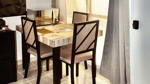 A dining area with a table, chairs, and a window with curtains. - Confort Condo with semi-Olympic pool, Wifi, AC, Grill, Balcony, Garden   (Playa del Carmen)