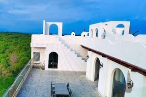 A white building with a staircase leading to a balcony, a table, and a chair on the balcony. - Destiny (Huidong)