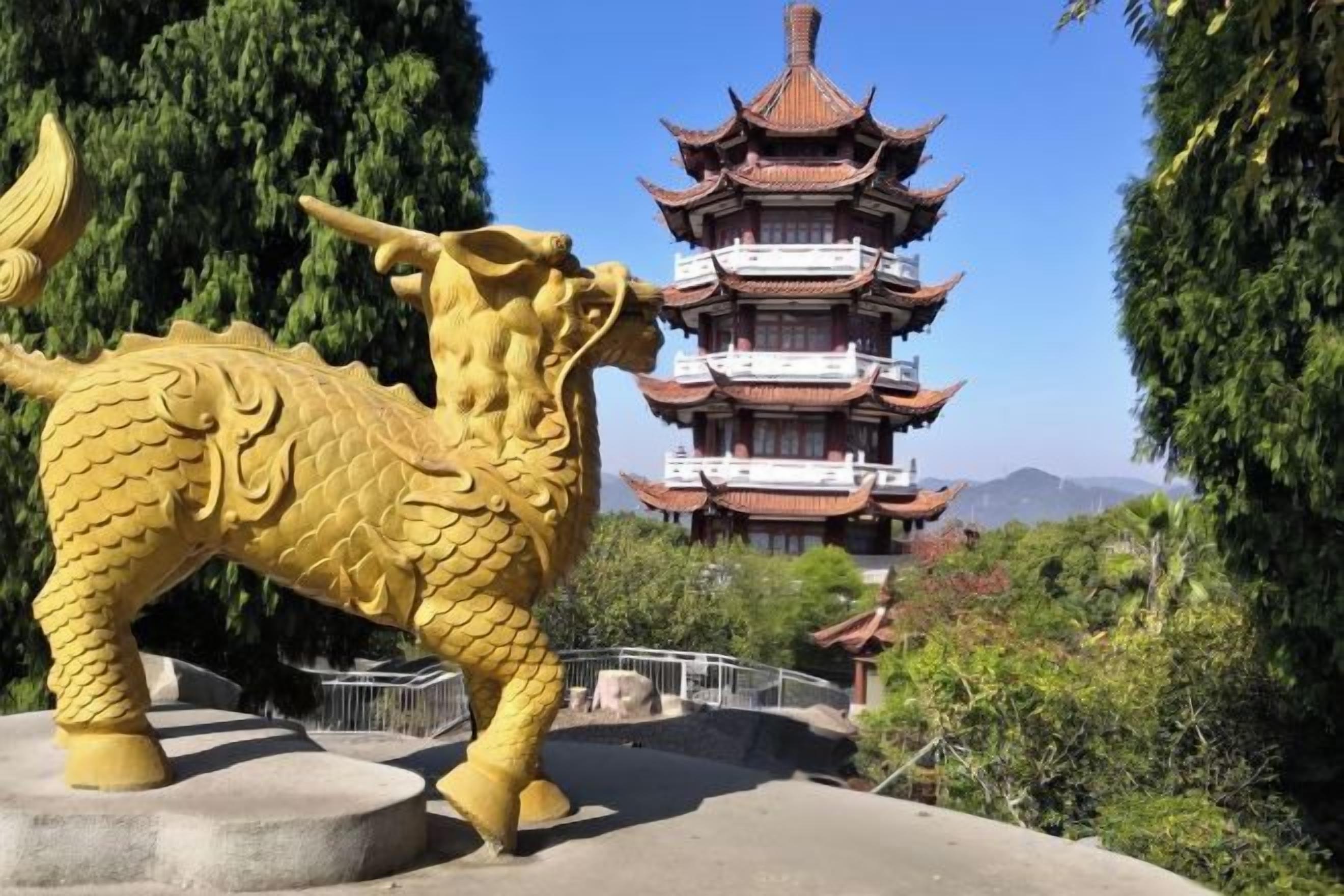 A large golden dragon statue in front of a traditional multi-tiered pagoda.