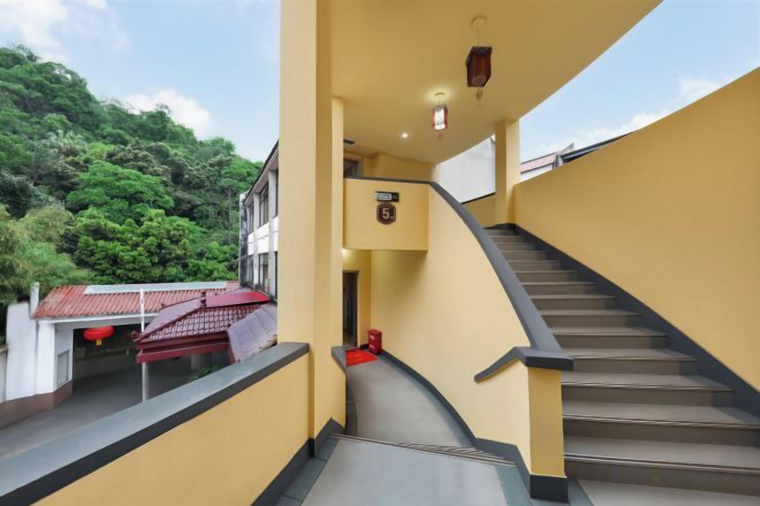 A staircase leading to a landing with a view of a building and greenery.