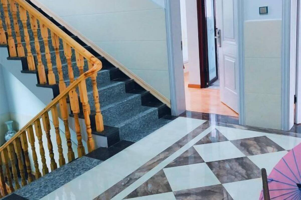 Un escalier avec des balustrades en bois, un sol à carreaux et une porte donnant sur une autre pièce.