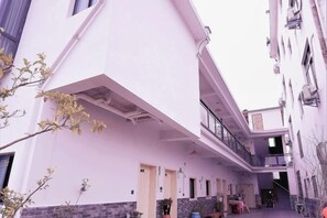 Une ruelle étroite entre deux bâtiments, avec une structure à toit plat sur la gauche et un immeuble à plusieurs étages sur la droite.