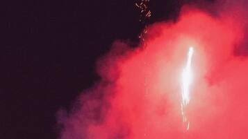 Ein Feuerwerk mit hellem Licht und rotem Rauch vor dunklem Hintergrund.