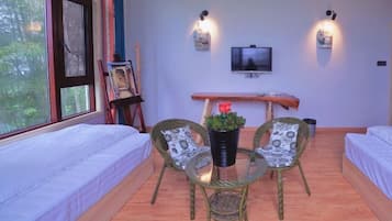 Una habitación con dos camas, televisión, un cuadro y una mesa con sillas.
