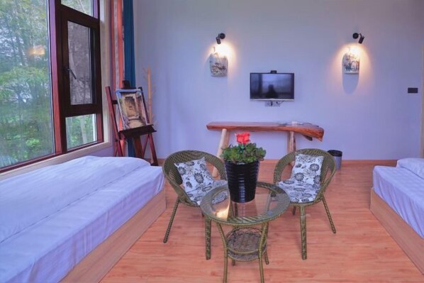 Une chambre avec deux lits, une télévision, un tableau et une table avec des chaises.
