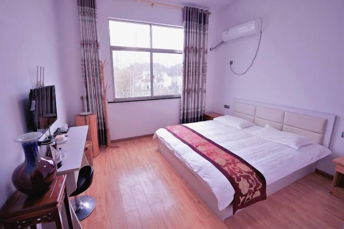 Une chambre à coucher avec un lit, un bureau, une chaise, une télévision et une fenêtre.