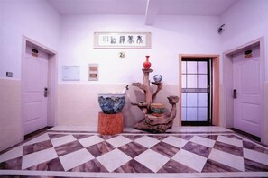 Un hall d’hôtel comprenant un comptoir d’enregistrement, un bureau d’accueil et une fontaine décorative.