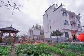 A traditional building with a balcony, surrounded by a garden with plants and a gazebo. - Wuyuan Wo Shun House (Wuyuan)