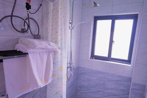 Une salle de bain avec une douche, une fenêtre et un porte-serviettes.