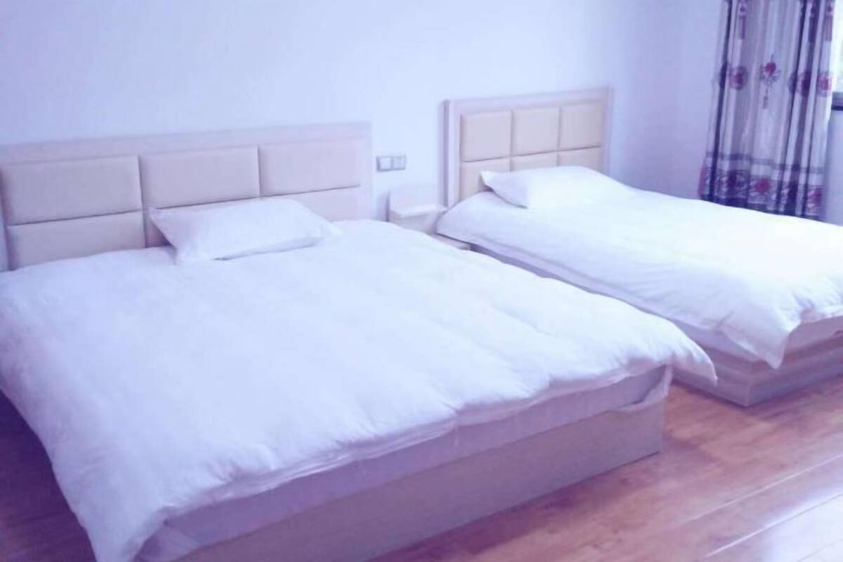 Un lit double avec une tête de lit, une table de chevet et un rideau.