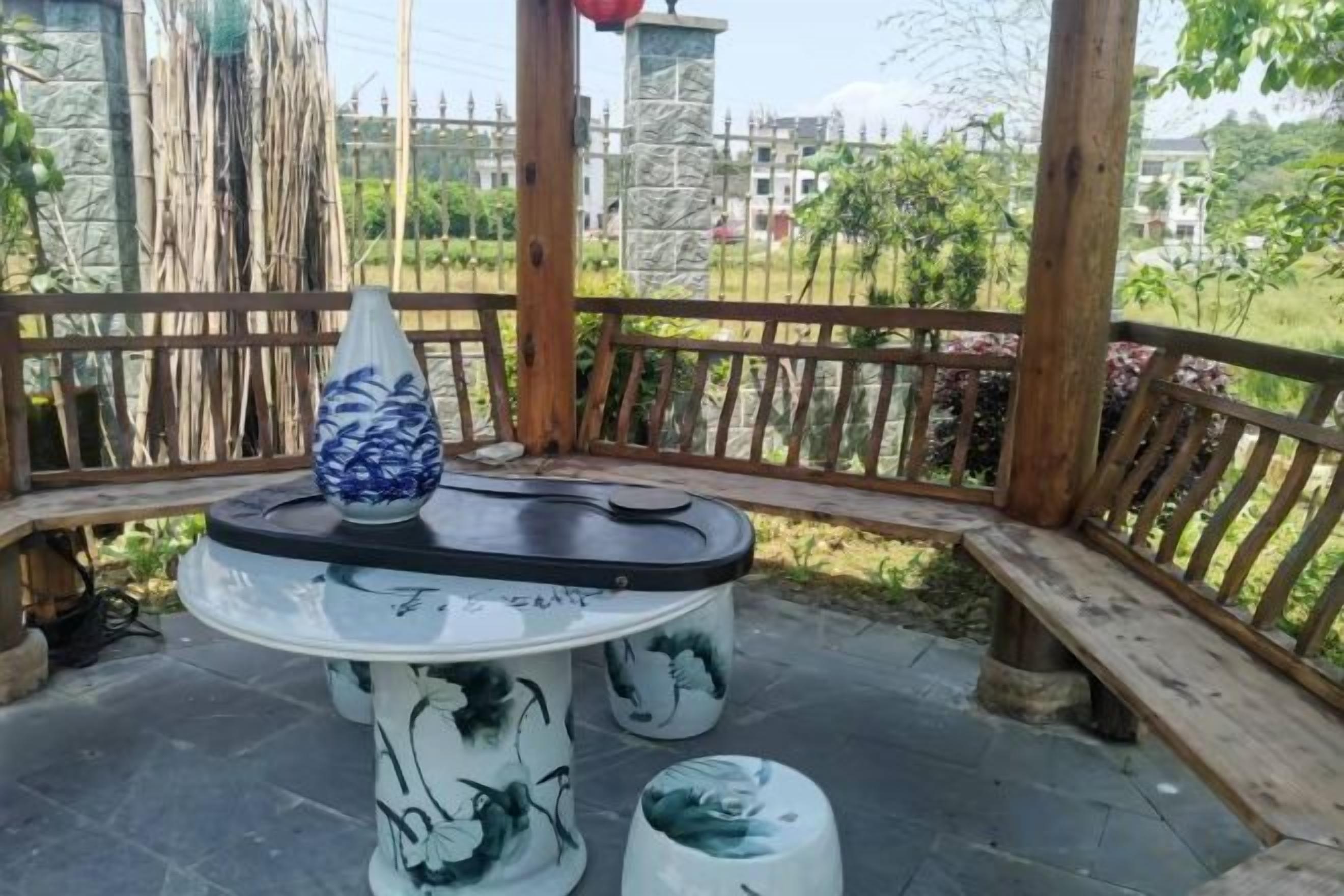 Un mirador con una mesa redonda y un florero, rodeado de una valla de madera y follaje.