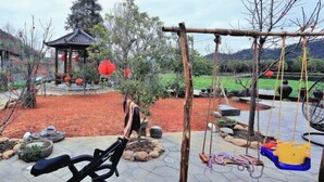 Un jardin agrémenté d’un belvédère, de balançoires et d’appareils de musculation.