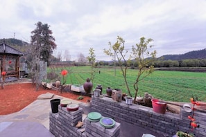 Un jardin agrémenté d’un mur en briques, de différents jardinières et d’un pavillon de style traditionnel.