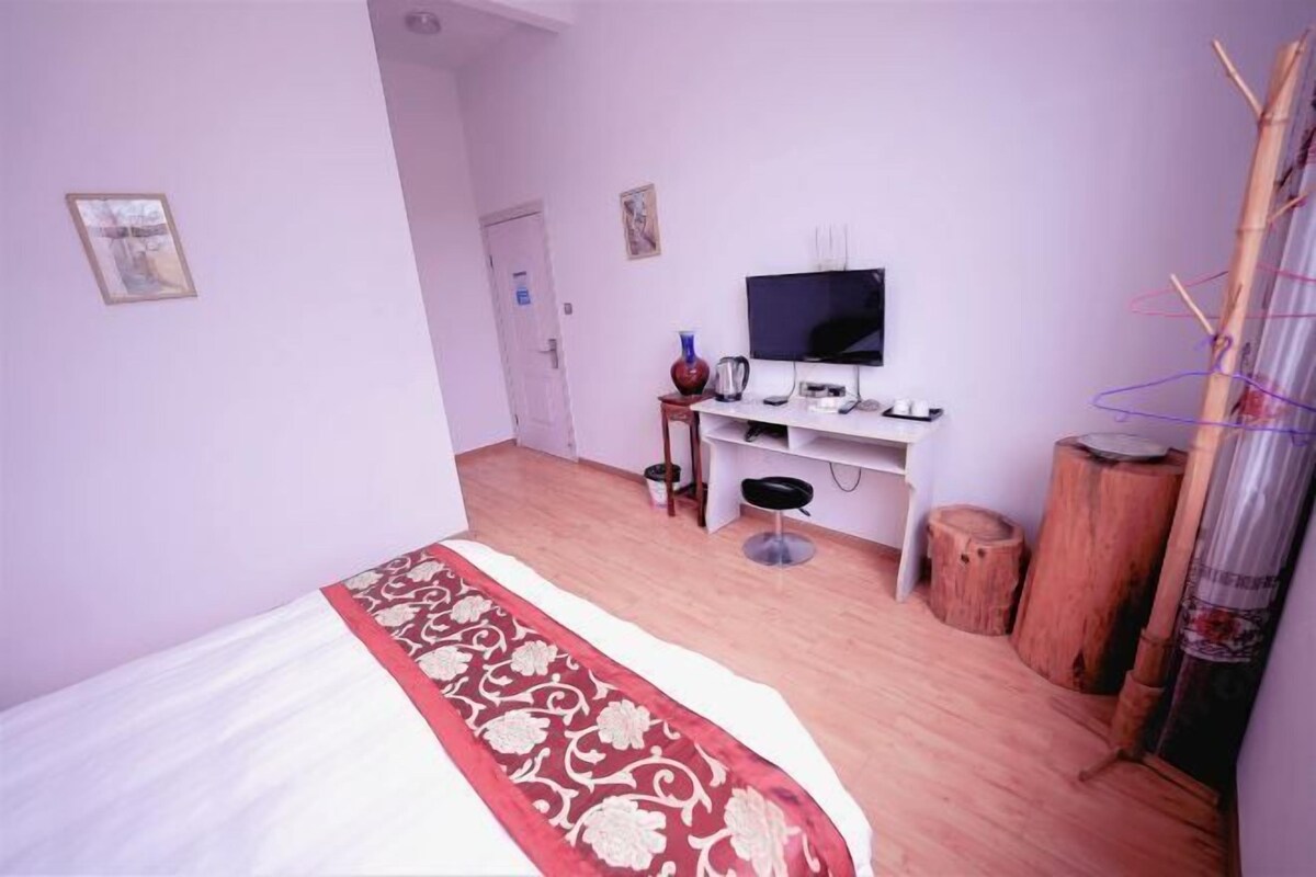 Une chambre à coucher avec un lit, une télévision, un bureau et une chaise.