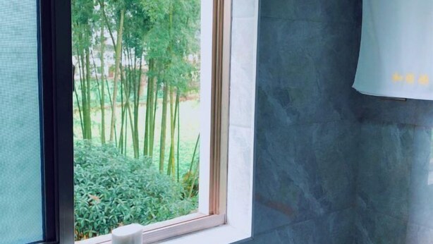 Une salle de bain avec une fenêtre, un distributeur de serviettes blanches et un mur en marbre.