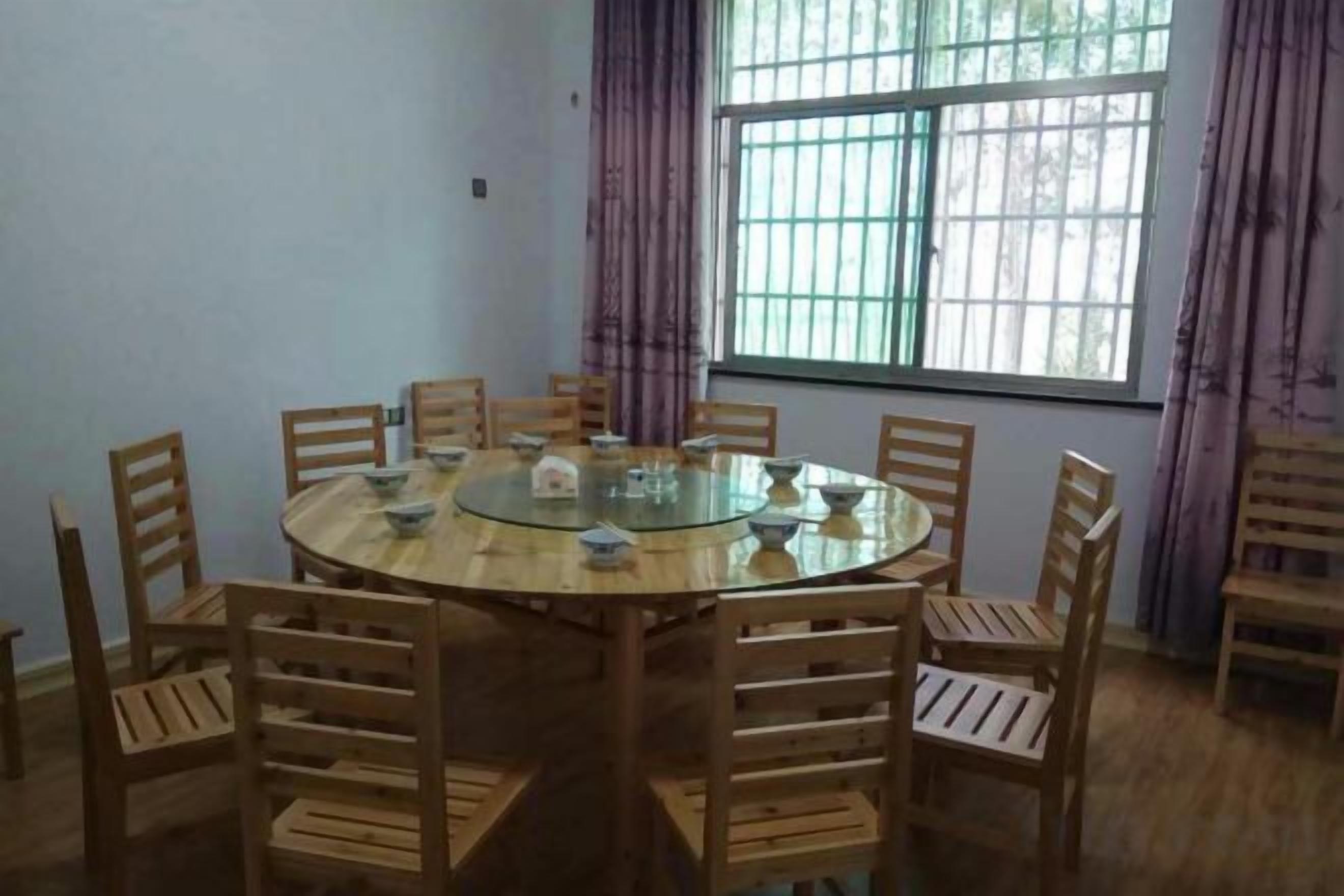 Uma mesa de jantar redonda com cadeiras, uma janela com grades e cortinas.