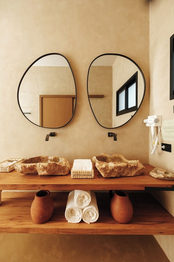 Une salle de bain avec deux miroirs ronds, un meuble-lavabo en bois et un porte-serviettes.