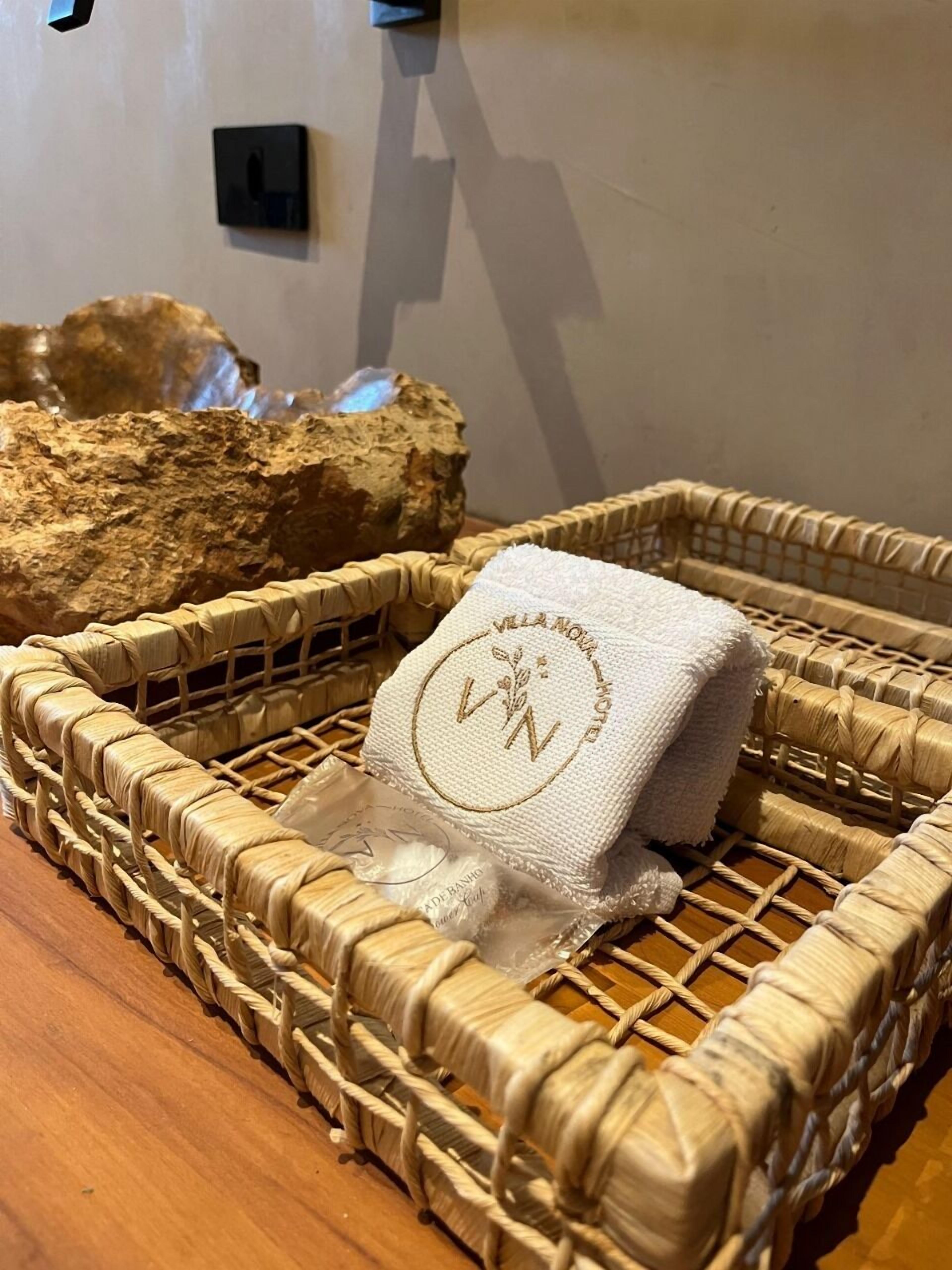 A woven basket with a towel and a small package on a wooden surface.