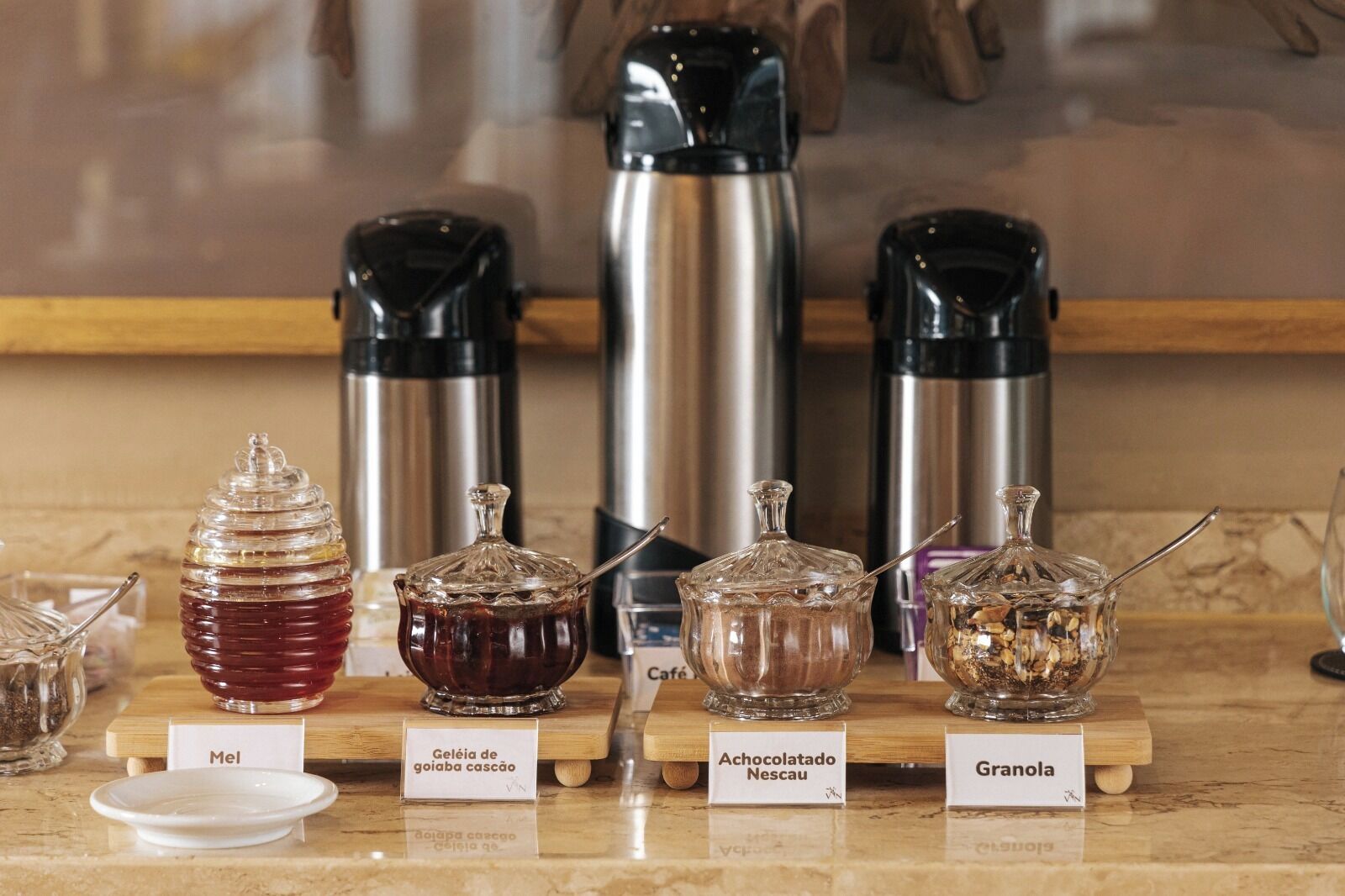 A display of various condiments on a wooden board with labels.