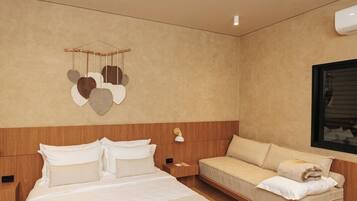 A modern hotel room with a large bed, a sofa, a wall-mounted heart decoration, and a window.