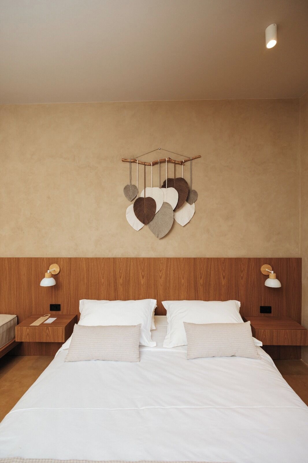 Une chambre à coucher avec une tête de lit en bois, une décoration en forme de cœur suspendue et deux lampes de chevet.