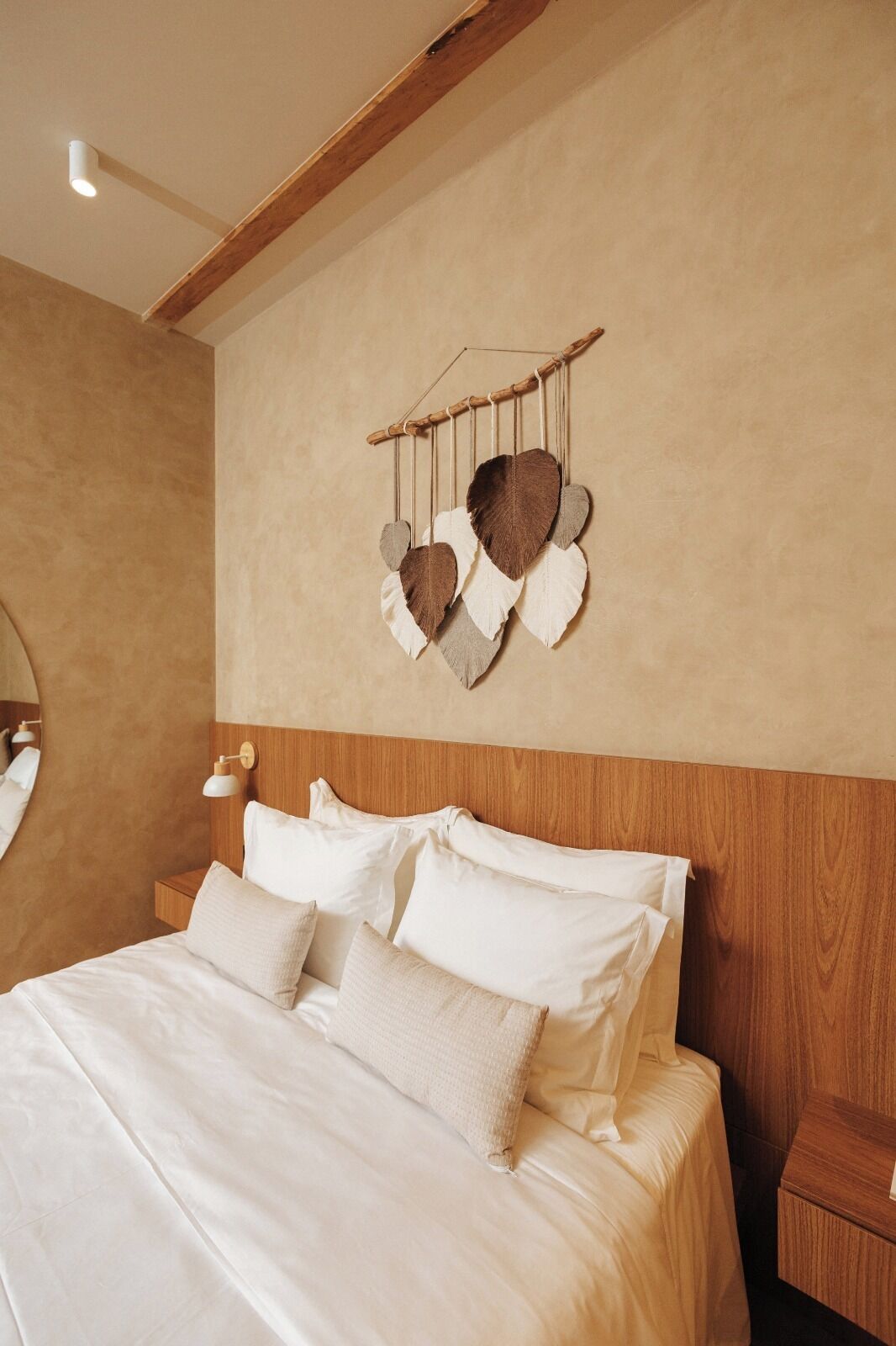 Un dormitorio con cabecera de madera, un adorno colgante en la pared y una lámpara de noche.