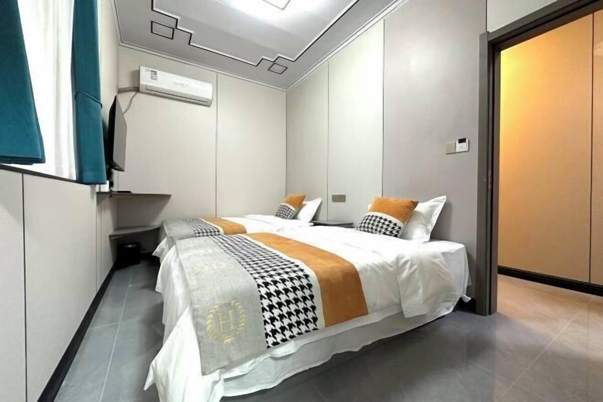A hotel room with two beds, a wardrobe, and a window with curtains.