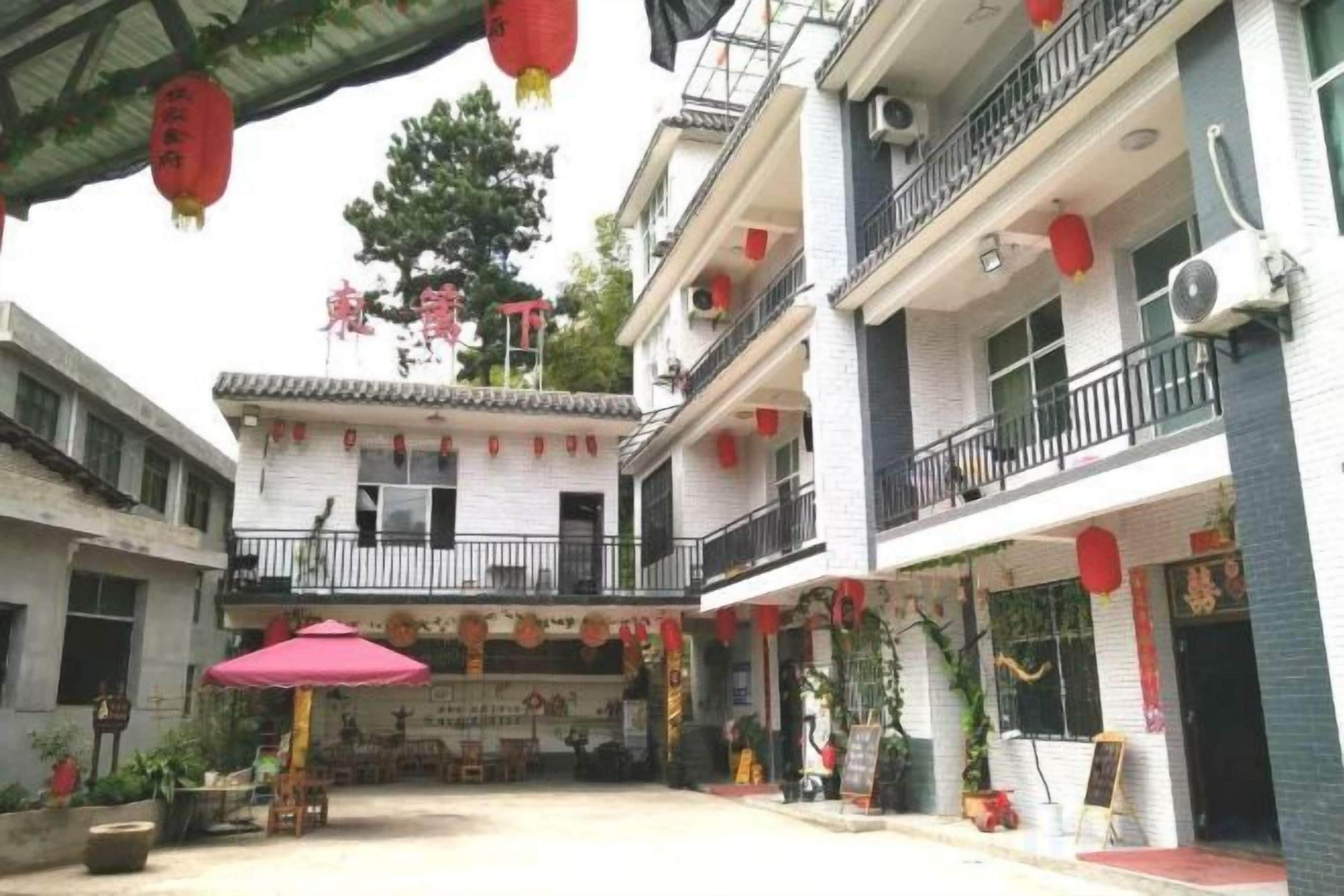 Un patio con arquitectura tradicional, que incluye un balcón y una zona de estar cubierta con una mesa y sillas.