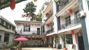 Un patio con arquitectura tradicional, que incluye un balcón y una zona de estar cubierta con una mesa y sillas.