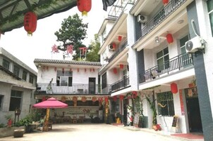 Un patio con arquitectura tradicional, que incluye un balcón y una zona de estar cubierta con una mesa y sillas.