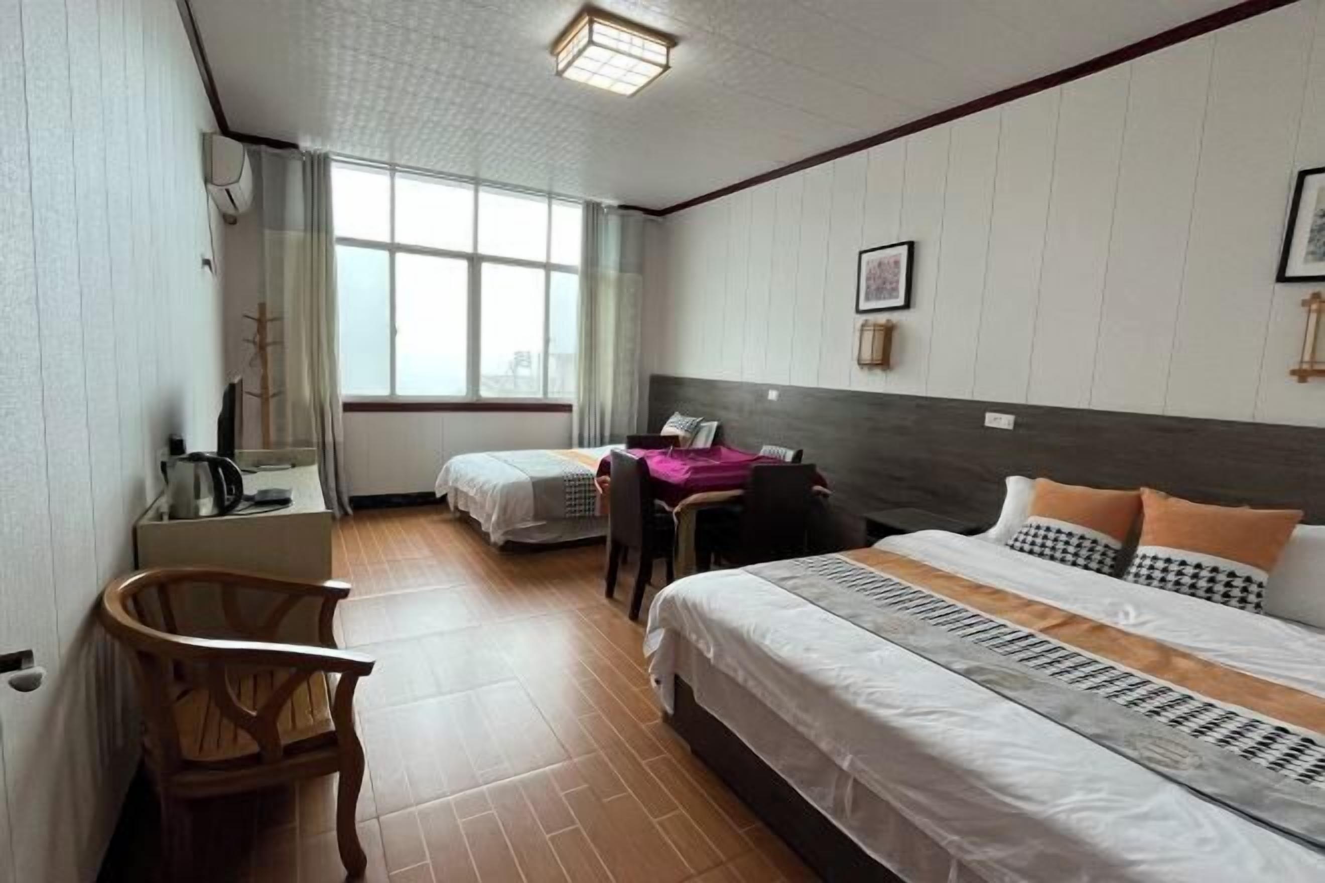 A hotel room with two beds, a desk, and a chair.
