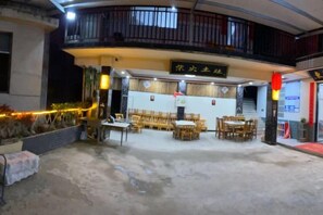 An indoor dining area with tables and chairs, a balcony with railings, and a sign above the entrance. - Bodaofeng Donglixia Farmhouse (Luotian County)