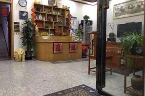 A reception area with a wooden counter, shelves with various items, and a potted plant.