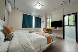 Una habitación de hotel moderna con una cama grande, un escritorio, televisión y una ventana con cortinas.