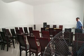 Un salón de conferencias con filas de sillas, un atril y un ventilador.