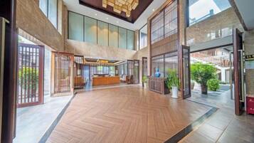 Eine großzügige Lobby mit Holzboden, einer Rezeption und großen Fenstern.