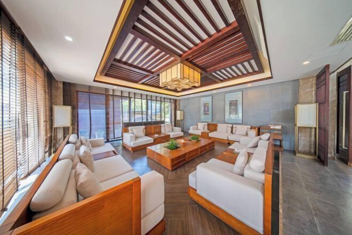 Uma sala de estar moderna com teto alto, vigas de madeira e uma mesa de centro.