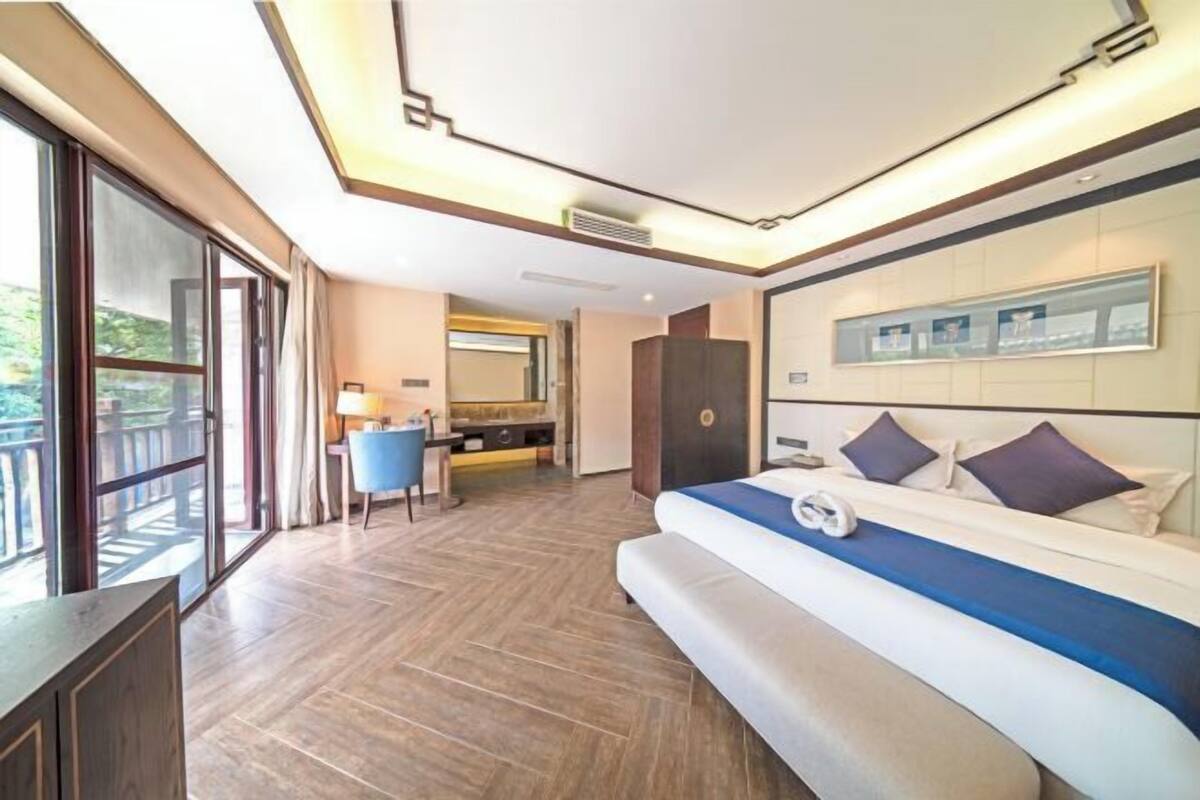 Quarto de hotel moderno com uma cama grande, uma escrivaninha e uma varanda.