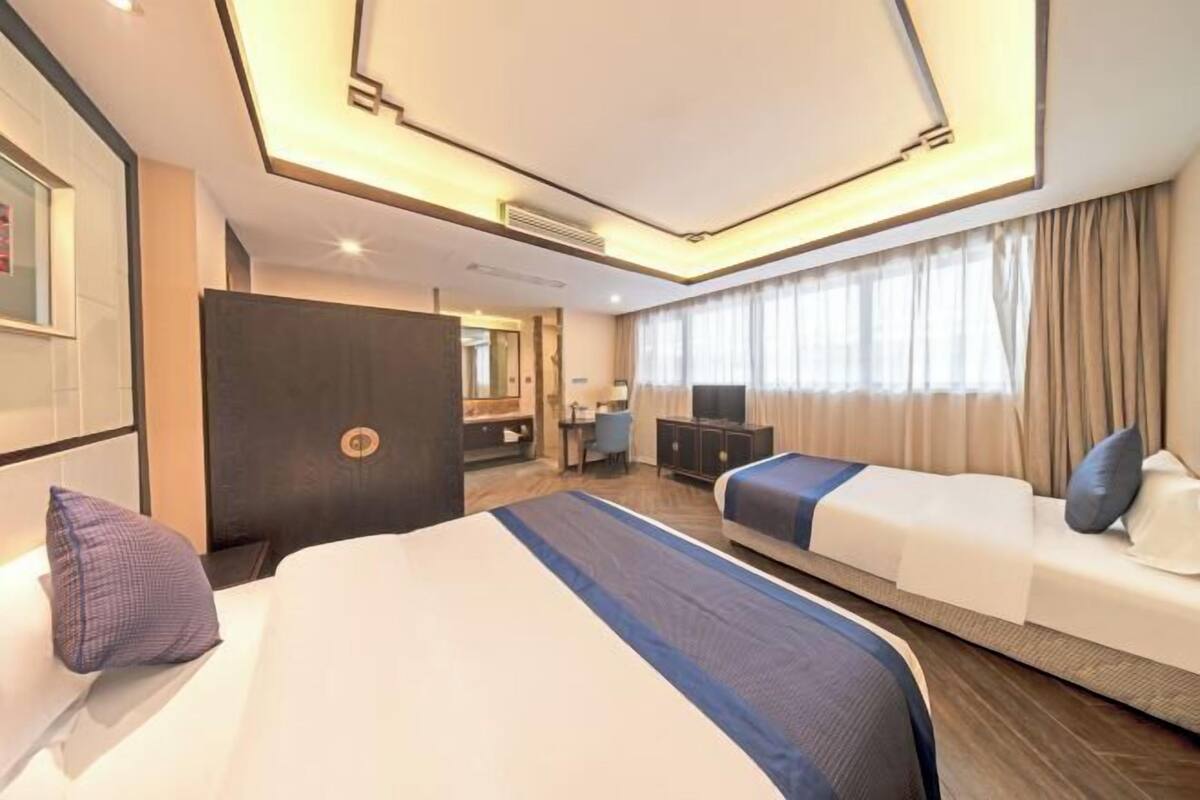 Quarto de hotel com uma cama grande, um sofá, uma escrivaninha e uma televisão.