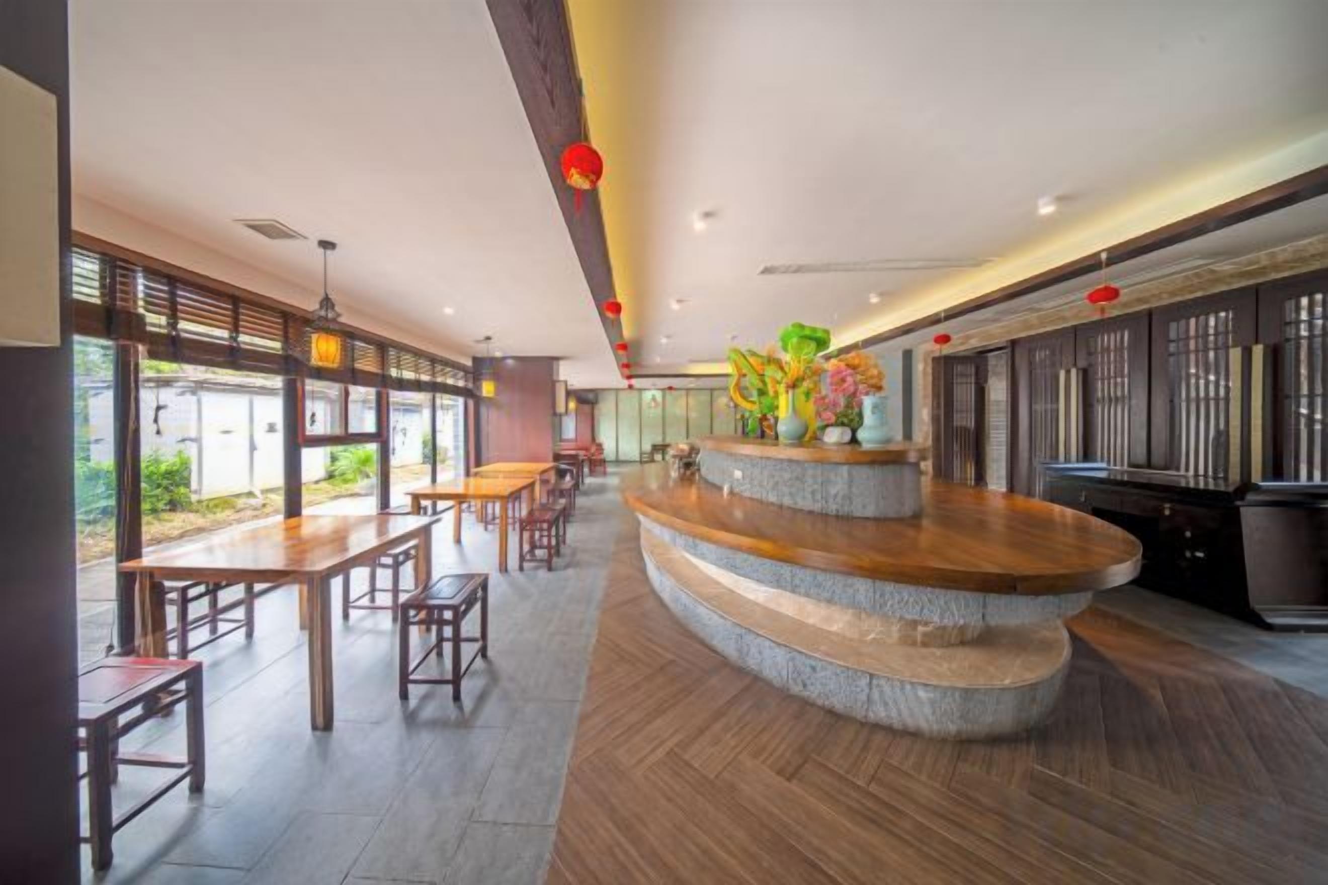 A restaurant with a curved wooden counter, multiple seating areas, and large windows.