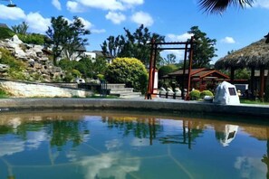 A tranquil outdoor area with a clear pool, a wooden gazebo, and a thatched-roof structure. - Songqin Chinese Inn · Wenquan Homestay (Caotang Millennium Ancient City Tourist Area) (Weng'an County)